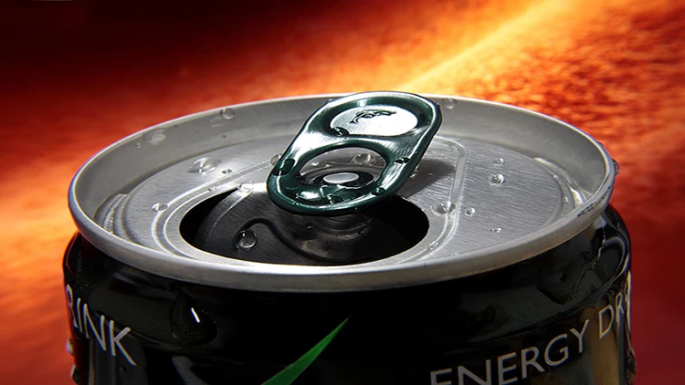 A closeup photo of an opened can of energy drink with orange fiery background.