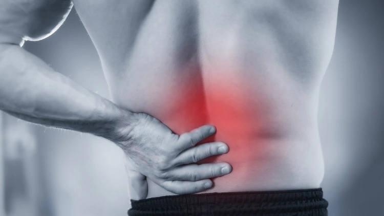 A man holding his lower back muscle with red around it, it seems like the lower back is in pain.