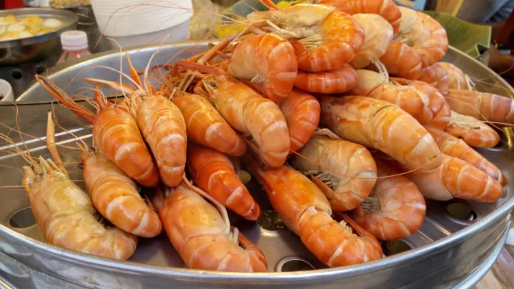 Around twenty-seven pieces of cooked garlic prawn placed in a silver steamer plate.