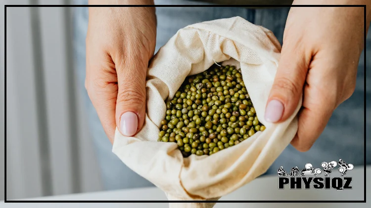 A woman with beige-colored nails, dressed in denim pants, is holding a white bag filled with countless green mung beans and wondering if mung beans are keto-friendly.