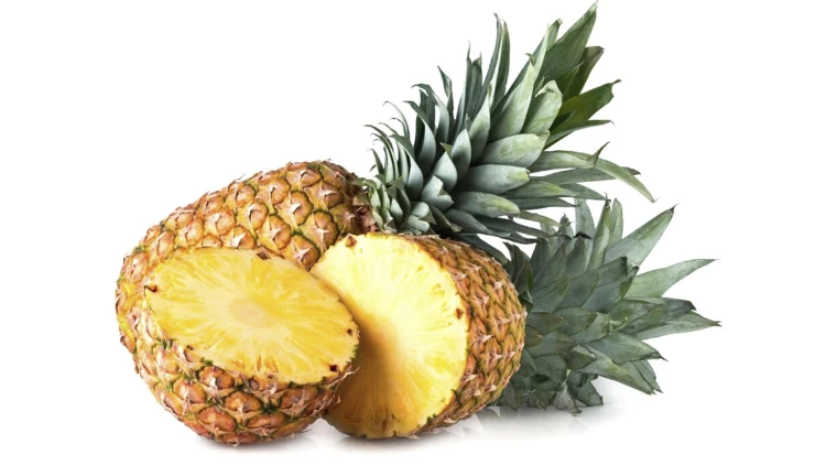 A whole pineapple and a halved pineapple placed on a white background.