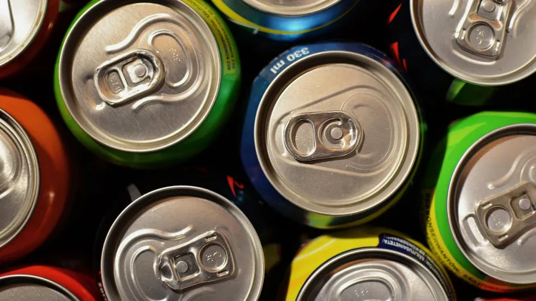 A top-down view of a group of energy drink cans, featuring various colors and textures on the surface of the cans, the cans are arranged in a neat pattern and their tops are visible, ready to be opened for a refreshing burst of energy.