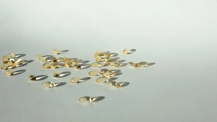 A bunch of clear, gold-colored supplements with visible shadows are placed on a white background.