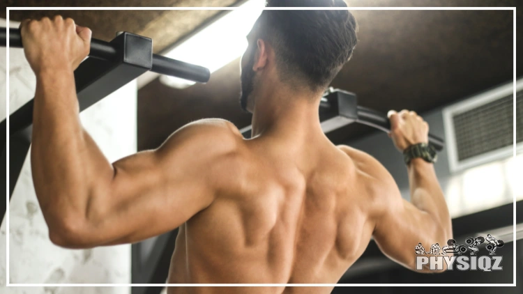 A tan shirtless and bearded man with black hair, a buzz cut and watch on his right wrist wonders what muscles do pull ups work while lifting himself up on a pull up bar in a pronated wide grip.