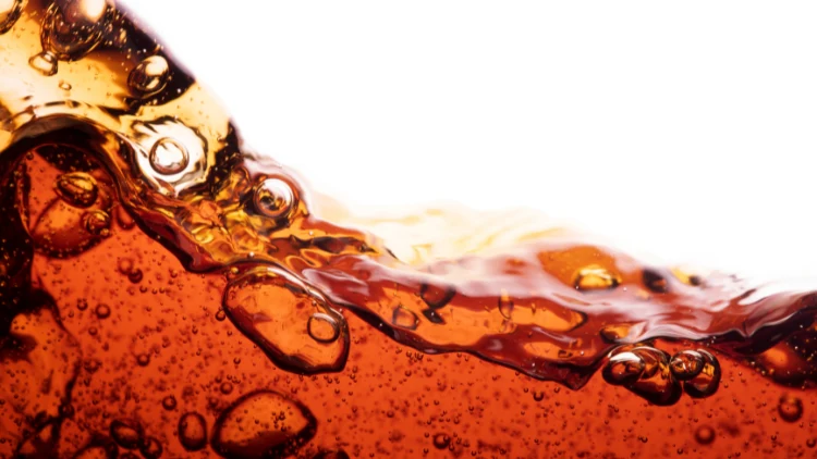 A splashing liquid of a refreshing soda Coke with bubbles against a white backdrop.