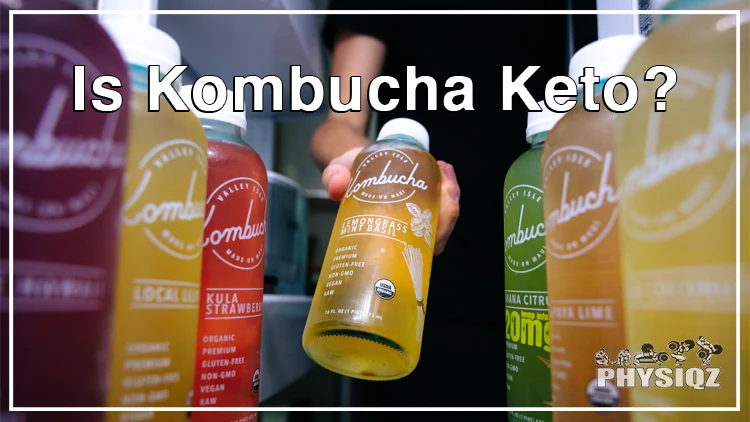 A person wearing a black t-shirt and pants is holding a bottle of low carb kombucha that is filled with orange liquid with a label that says 'Kombucha' from a fridge with several other beverage bottles from the same brand but in different flavors and colors such as strawberry, citrus, and lime, and colors ranging from purple, orange, green and red